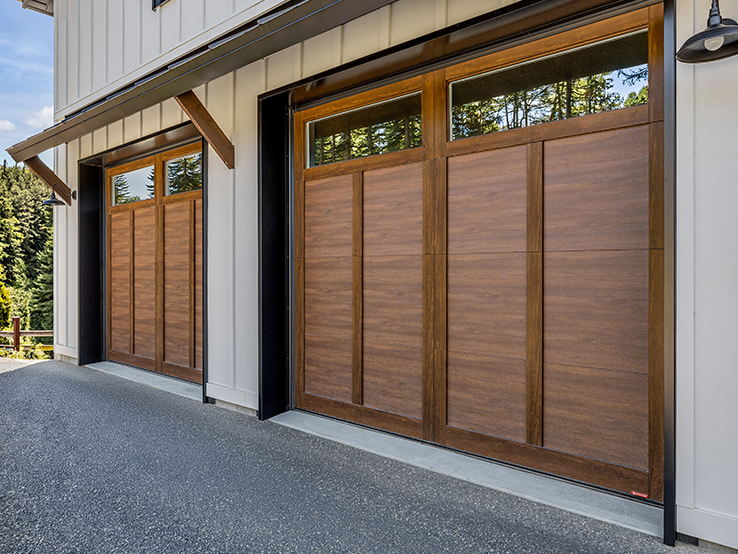 Garaga residential garage door with a Chocolate Walnut faux-wood finish, the E-12 design, matching overlays and windows.