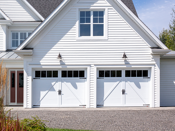 Garaga residential garage door in Ice White with the E-22 design, matching overlays and four vertical windows.