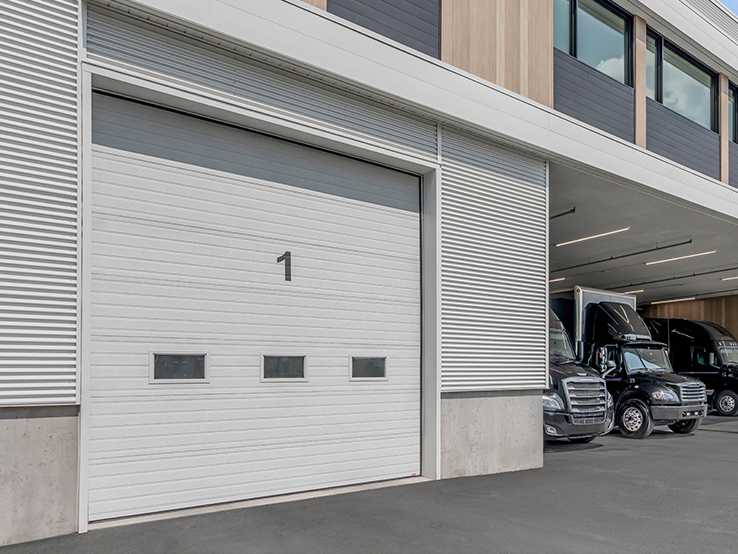 Garaga G-5000 commercial garage doors in Ice White, 12' x 14', Grooved design, Standard windows and Uniform woodgrain steel.