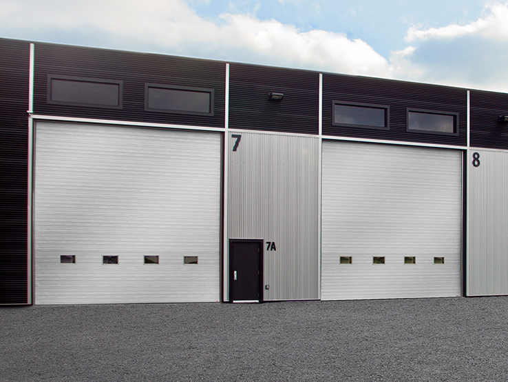 Garaga G-5000 commercial garage doors in Silver, 20' x 20', Grooved design, windows and Uniform woodgrain steel.
