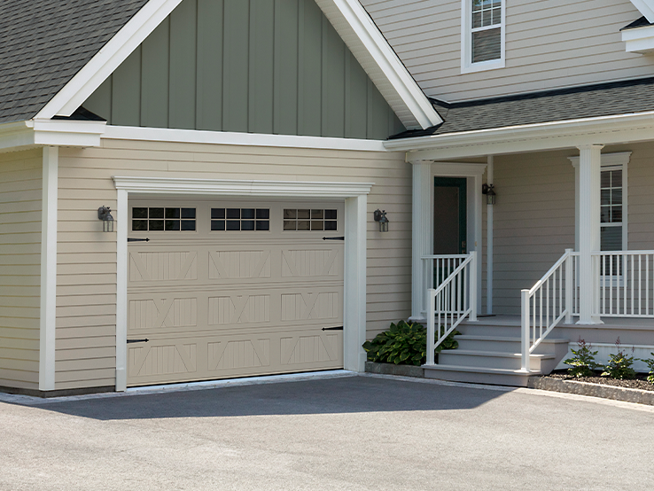 Garaga residential garage door in Sandstone with the X design, a beadboard base and Stockton window inserts.