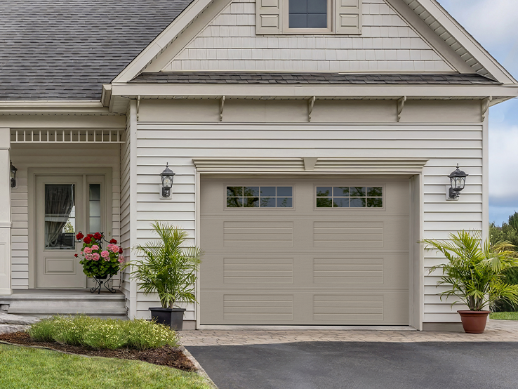 Garaga residential garage door in Sandstone with the Louver Four Slat design and Stockton window inserts.