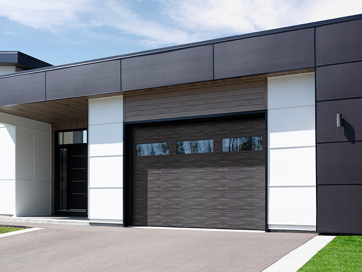 Garaga residential garage door with a Weathered Grey faux-wood finish, the Moderno Multi design and windows.