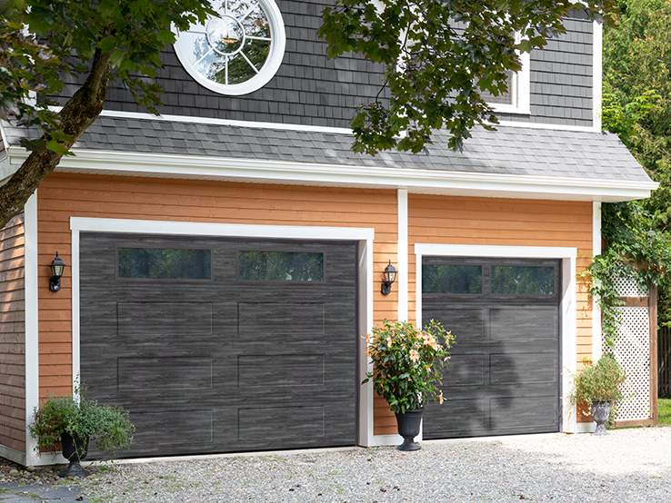 Garaga residential garage door with a Weathered Grey faux-wood finish, the Recessed Long design and Clear glass.