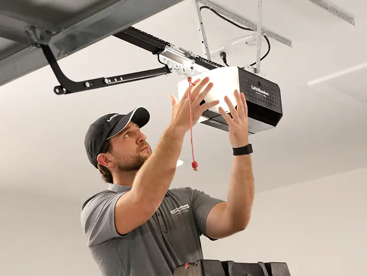 Technicien installant un ouvre-porte de garage LiftMaster 2420L.