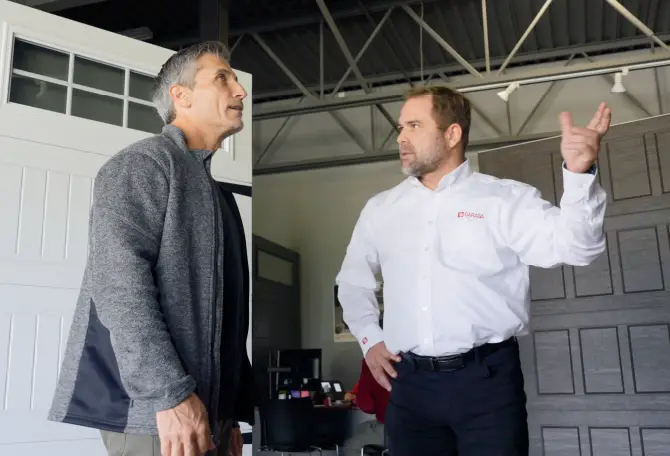 A sales representative showing a customer Garaga garage doors on display in the showroom.